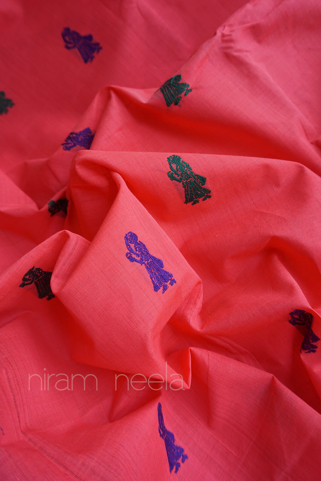 Close-up of pink fabric with woven patterns, featuring the brand 'niram neela'.