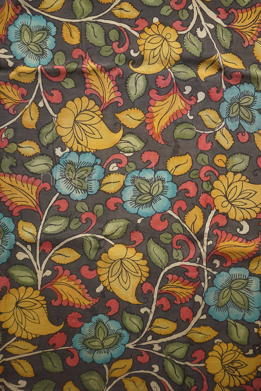 A close-up of a dark gray fabric featuring a colorful floral and paisley pattern with yellow, blue, red, and green motifs.