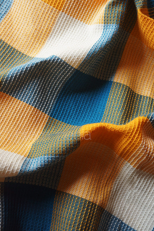 Close-up of a checkered fabric with orange, blue, and white pattern | Home linen by Niram Neela