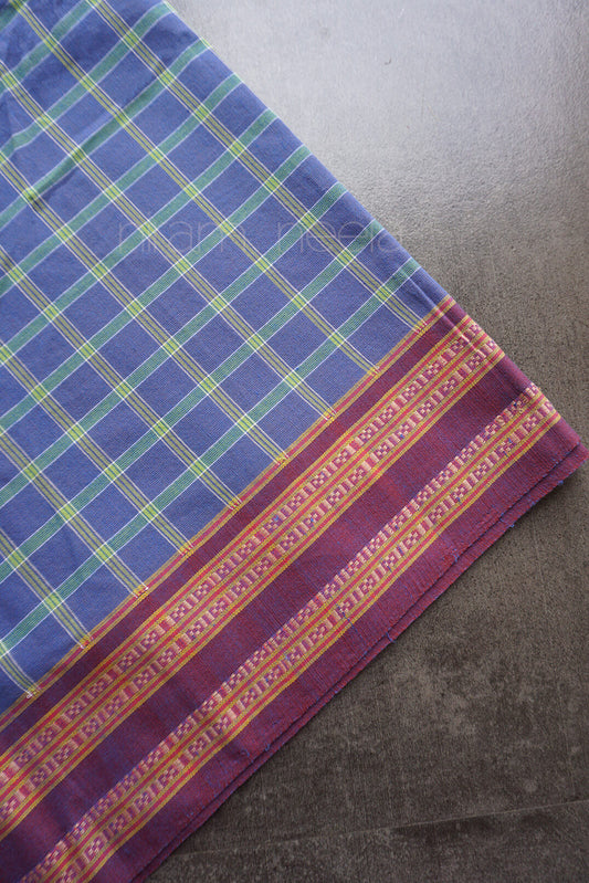 A blue and green checkered fabric with a maroon border against a dark grey background