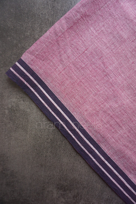 A close-up of an aubergine woven fabric, featuring a black border with thin white stripes, laid diagonally on a textured gray surface.