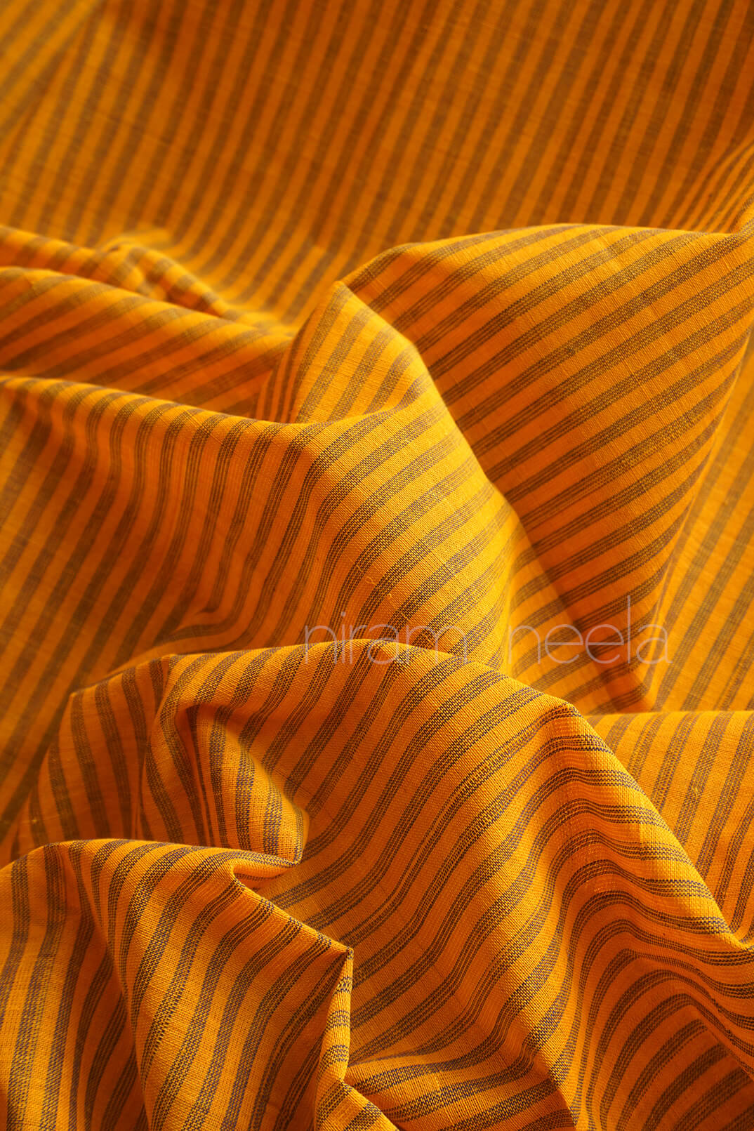 Close-up of mango yellow fabric with black stripes | Chettinad by Niram Neela