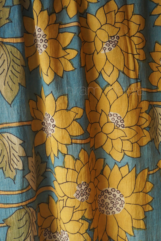 A close-up of a fabric  featuring large mustard yellow lotus flowers and green leaves on a muted teal-blue background.