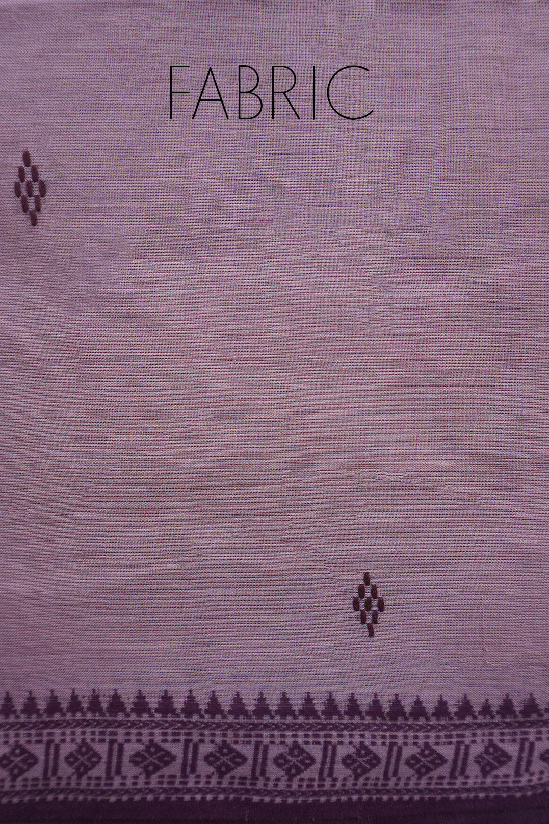 A close-up of a woven fabric sample in a muted mauve-purple color, featuring a dark patterned border along the bottom edge and the word 'FABRIC' printed at the top.