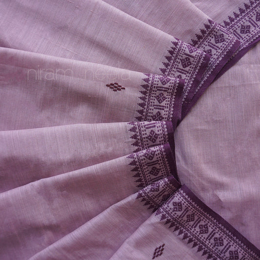 A close-up of a light lavender or lilac saree, with a contrasting dark purple border featuring geometric and floral patterns.
