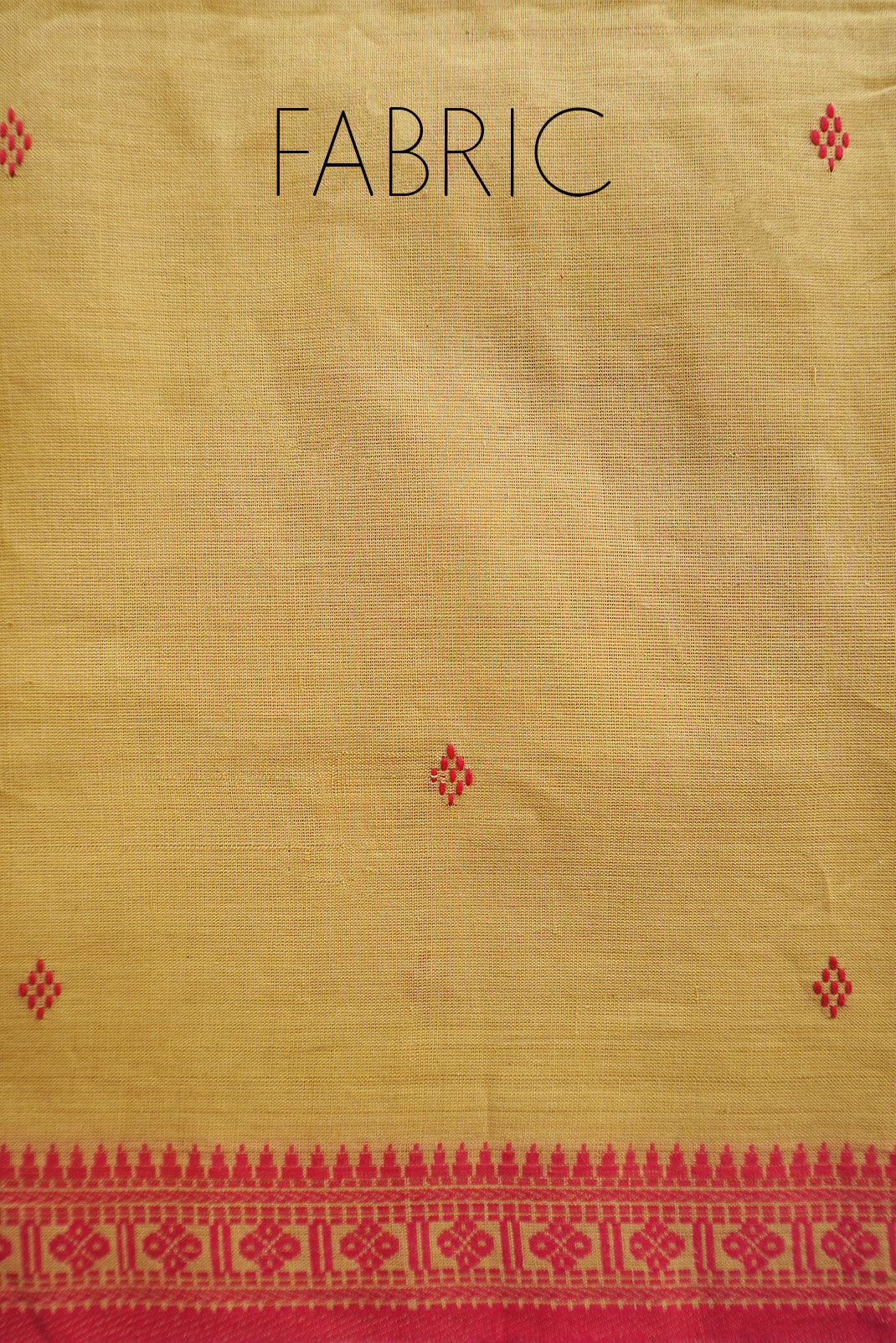 A close-up of a woven saree in warm beige yellow, with a red decorative border along the bottom and small red diamond motifs scattered across the surface. The word "FABRIC" is printed at the top.
