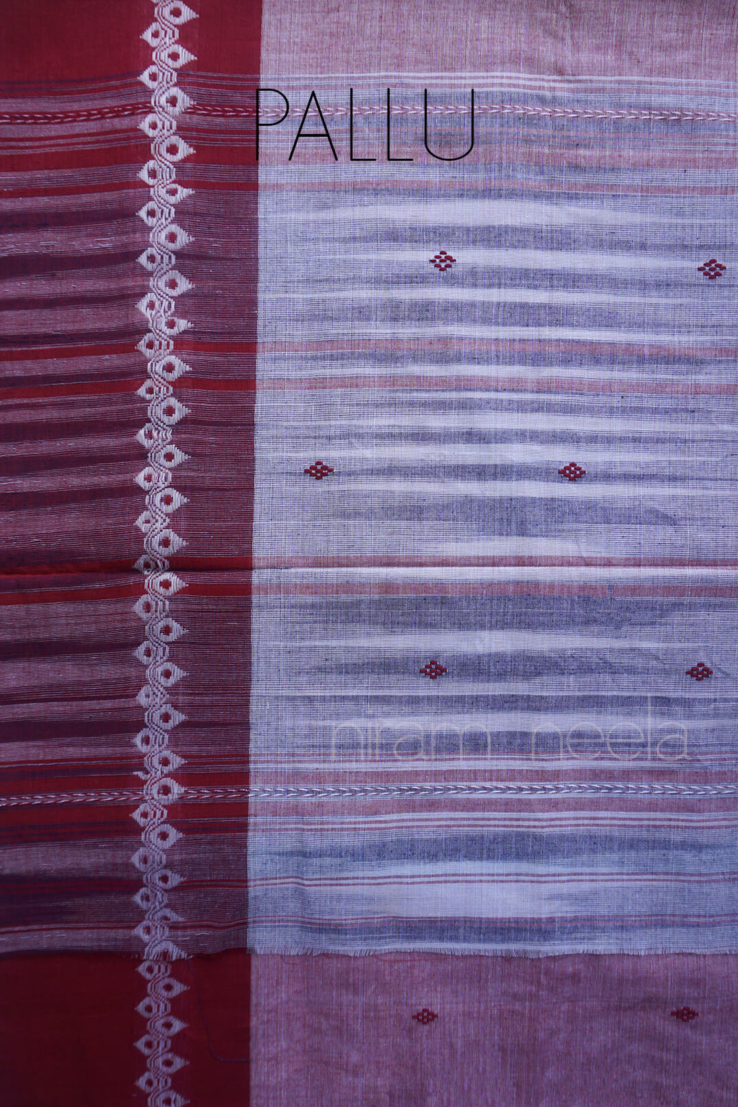 A close-up of a traditional Indian saree , likely cotton, featuring a deep red pallu with white geometric woven motifs, a light grey body with horizontal stripes, and small red diamond motifs.