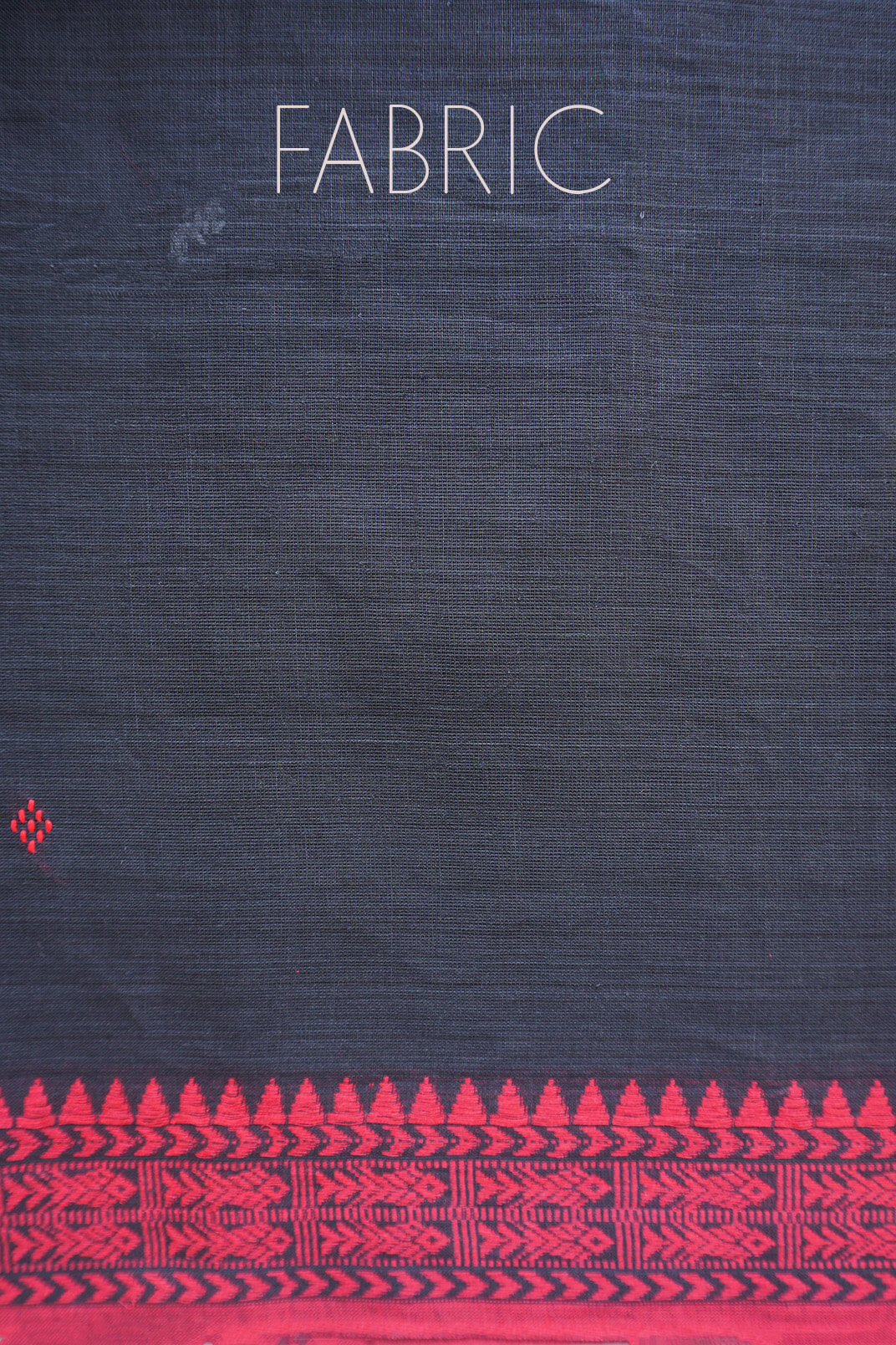 A close-up of dark gray fabric with a bright red patterned border along the bottom and the word 'FABRIC' printed near the top.