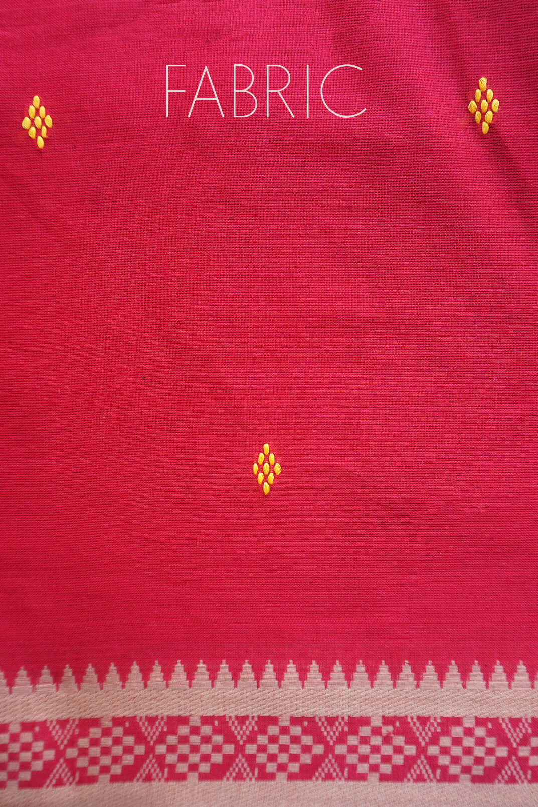 A close-up of a red fabric with a dust brown border pattern and small yellow embroidered motifs, with the word 'FABRIC' printed at the top.