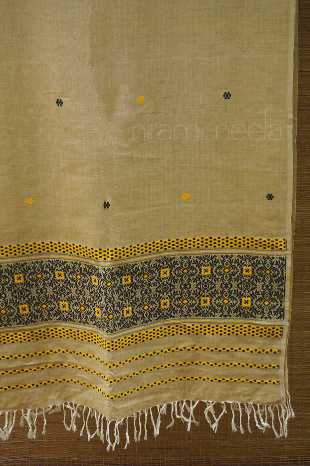 Beige fabric with black and yellow patterns on a wooden surface