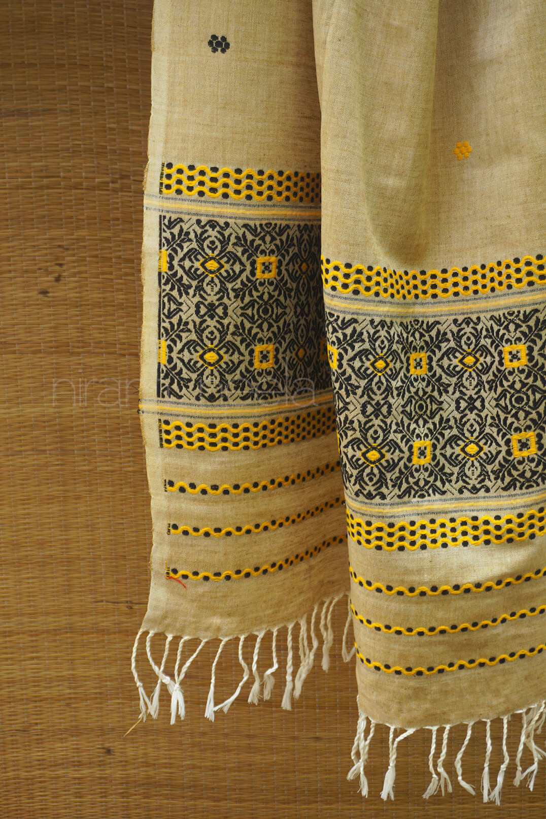 Silk scarf with intricate patterns and fringes on a wooden surface