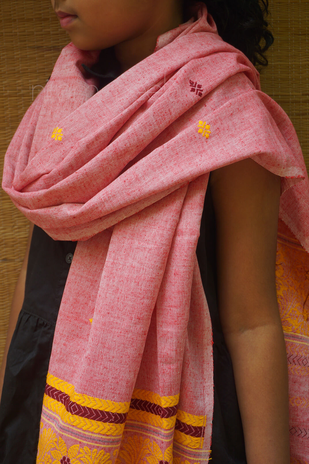 Person wearing a pink scarf with yellow accents against a wooden background