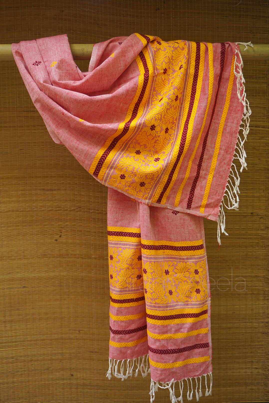 Pink and yellow patterned scarf with white fringe on a wooden background