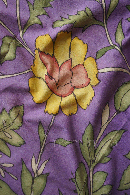 A close-up of a violet cotton fabric with a printed floral pattern featuring yellow petals, a dusty pink center, and green leaves.