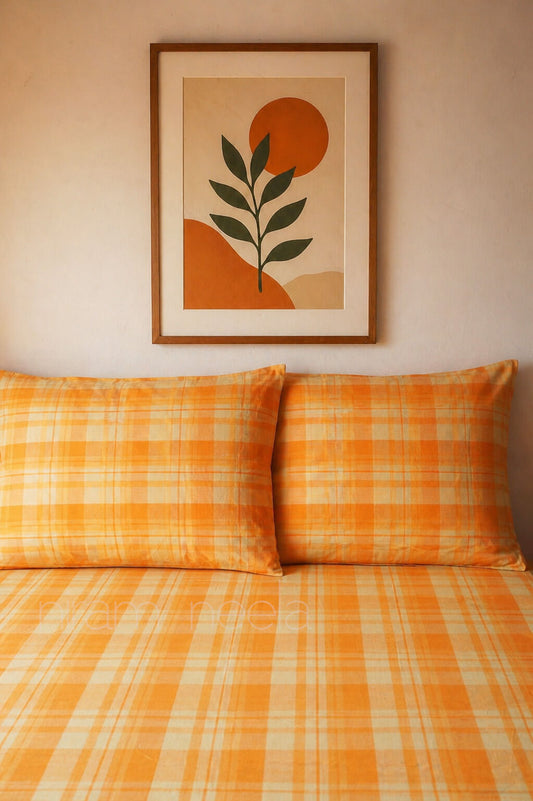 Orange checkered bedspread with matching pillows and a framed abstract art piece on the wall.