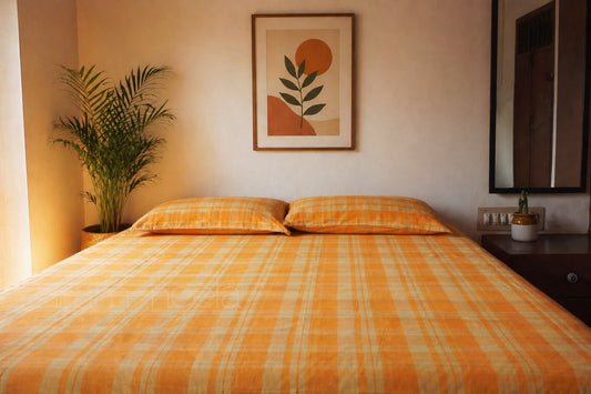 Bedroom with orange checkered bedspread, plant, and wall art.