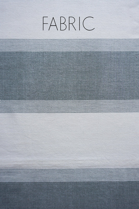A close-up of striped fabric with the word FABRIC printed at the top, showing alternating white and muted gray horizontal bands.