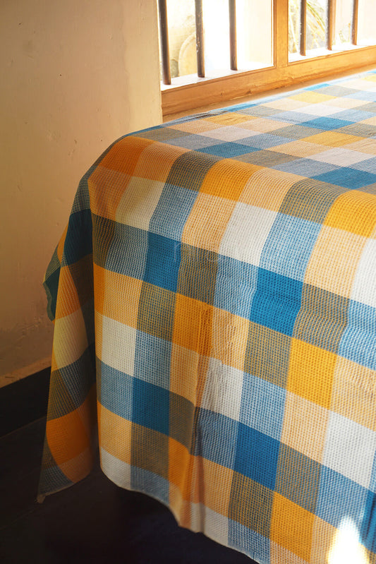 Checkered bedsheet on a bed with a window in the background | Home linen by Niram Neela