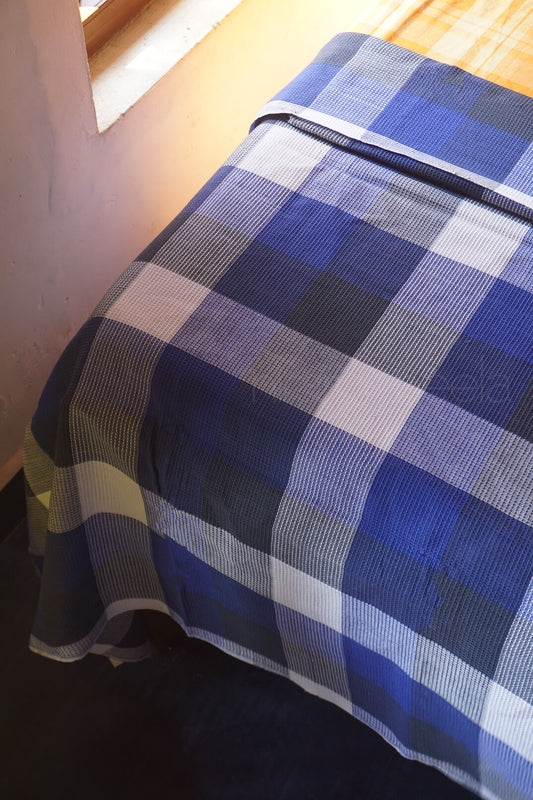 Blue and white checkered bedsheet on a bed corner | Home linen by Niram Neela