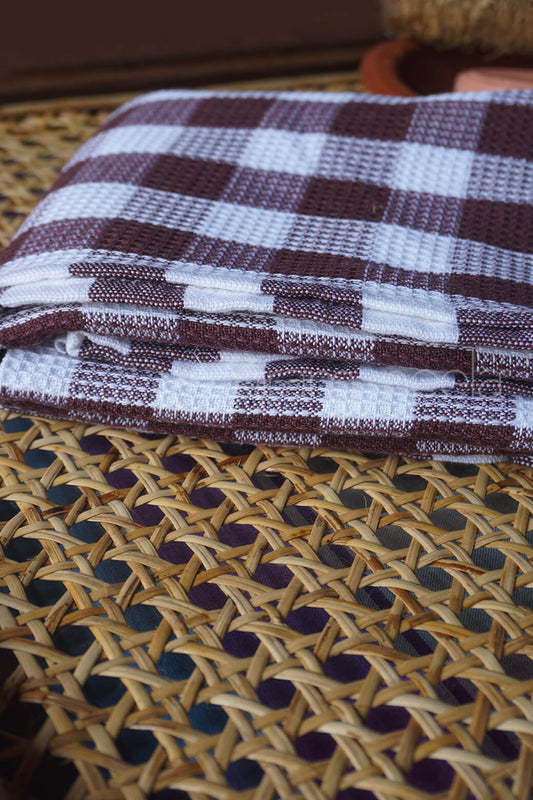 Folded fabric with a checkered pattern on a woven surface | Bed and bath by Niram Neela