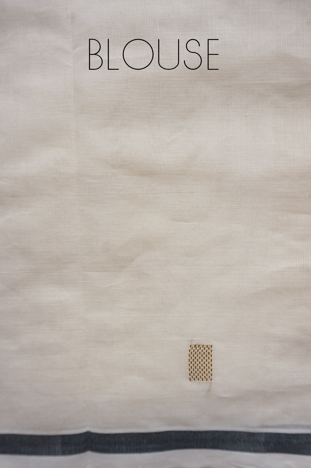 A close-up of a light beige fabric blouse material with a dark navy border along the bottom edge and the word 'BLOUSE' printed at the top.
