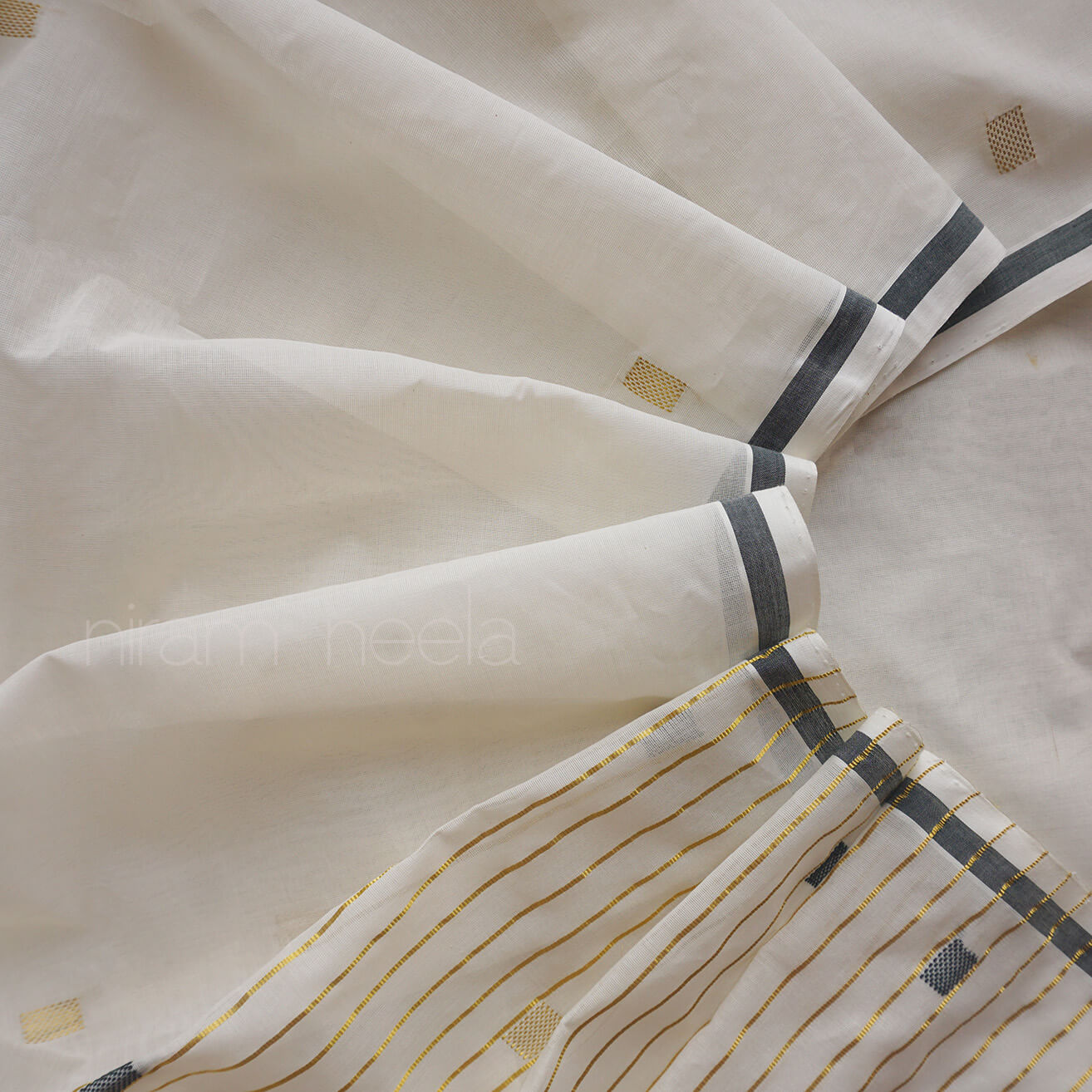A close-up of saree in warm off-white/cream, with dark green stripes and thin gold pinstripes near the lower right corner. No person, animal, or real environment is visible, so this is Product/Packaging rather than Lifestyle.