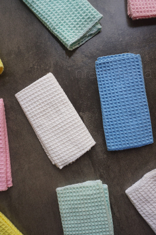 Colorful waffle-textured handkerchiefs on a dark surface | Niram Neela