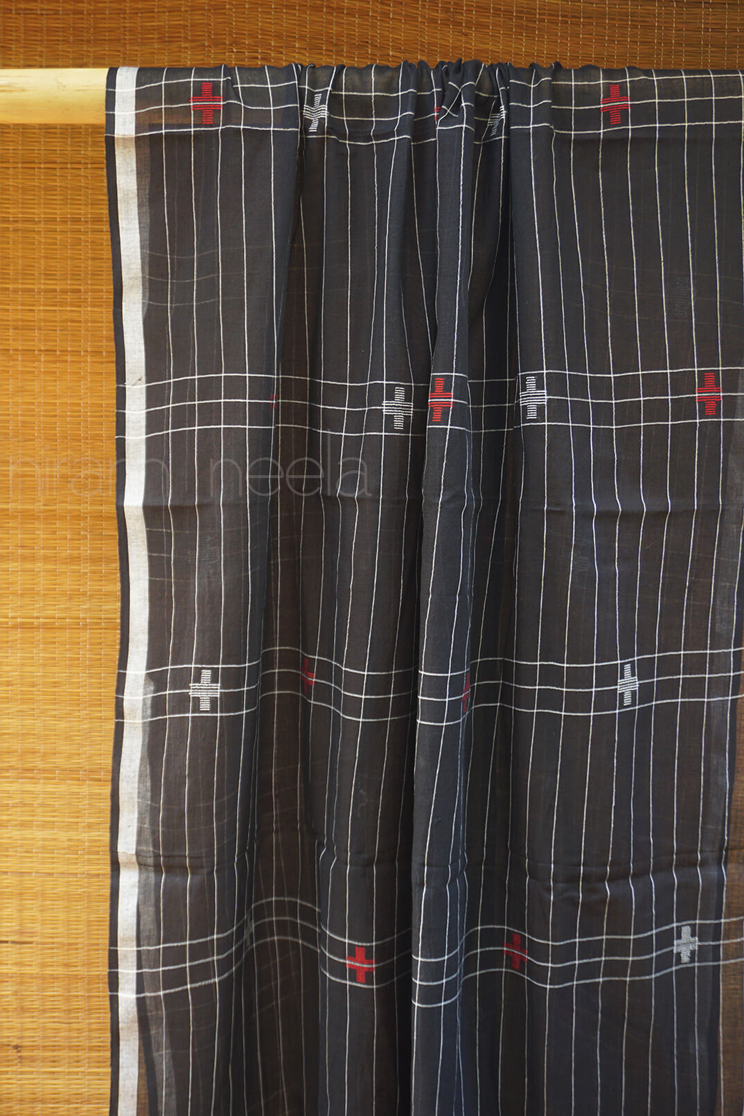 Black checkered shawl with white and red patterns on a wooden background