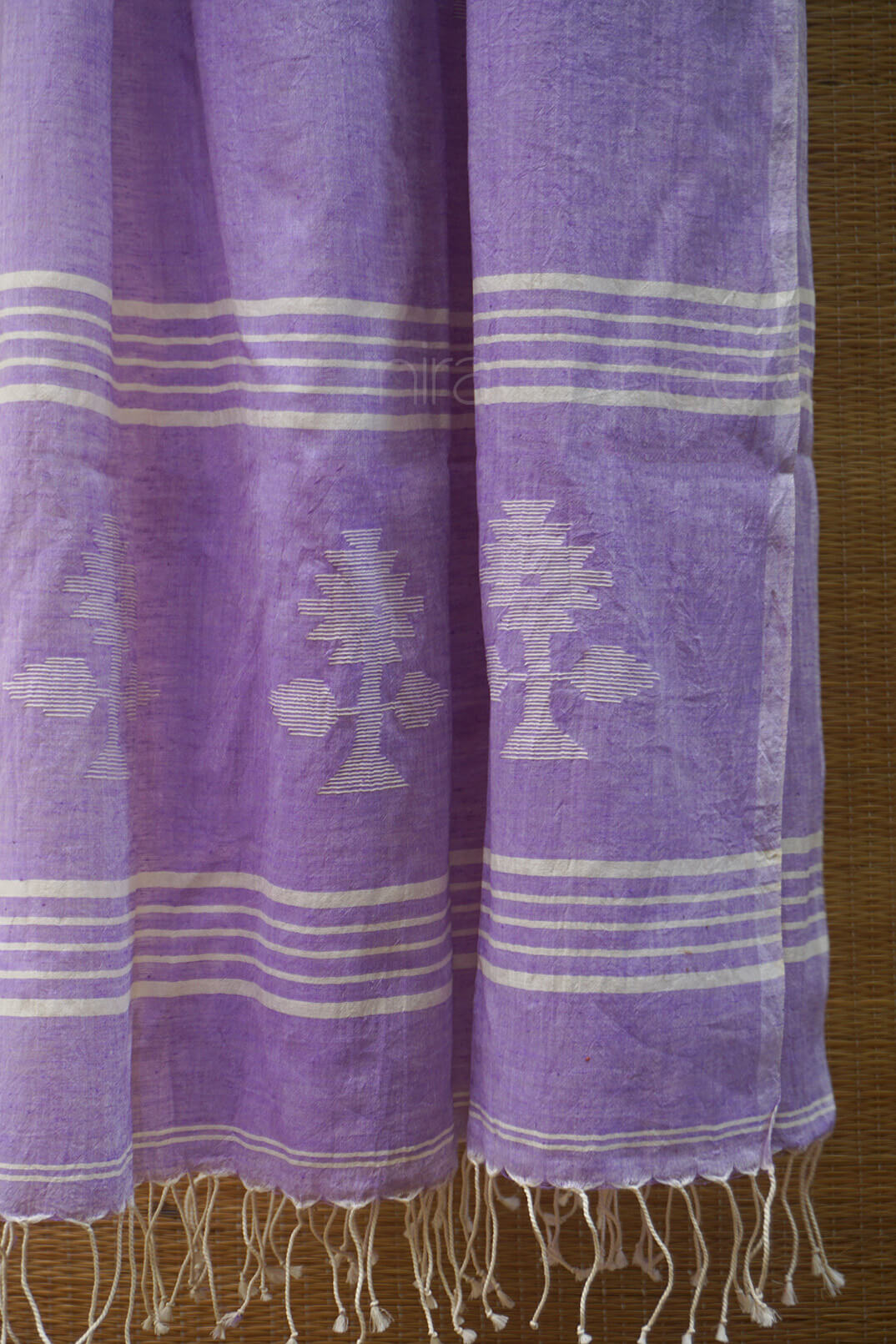 Soft violet scarf with white patterns and fringes on a wooden surface
