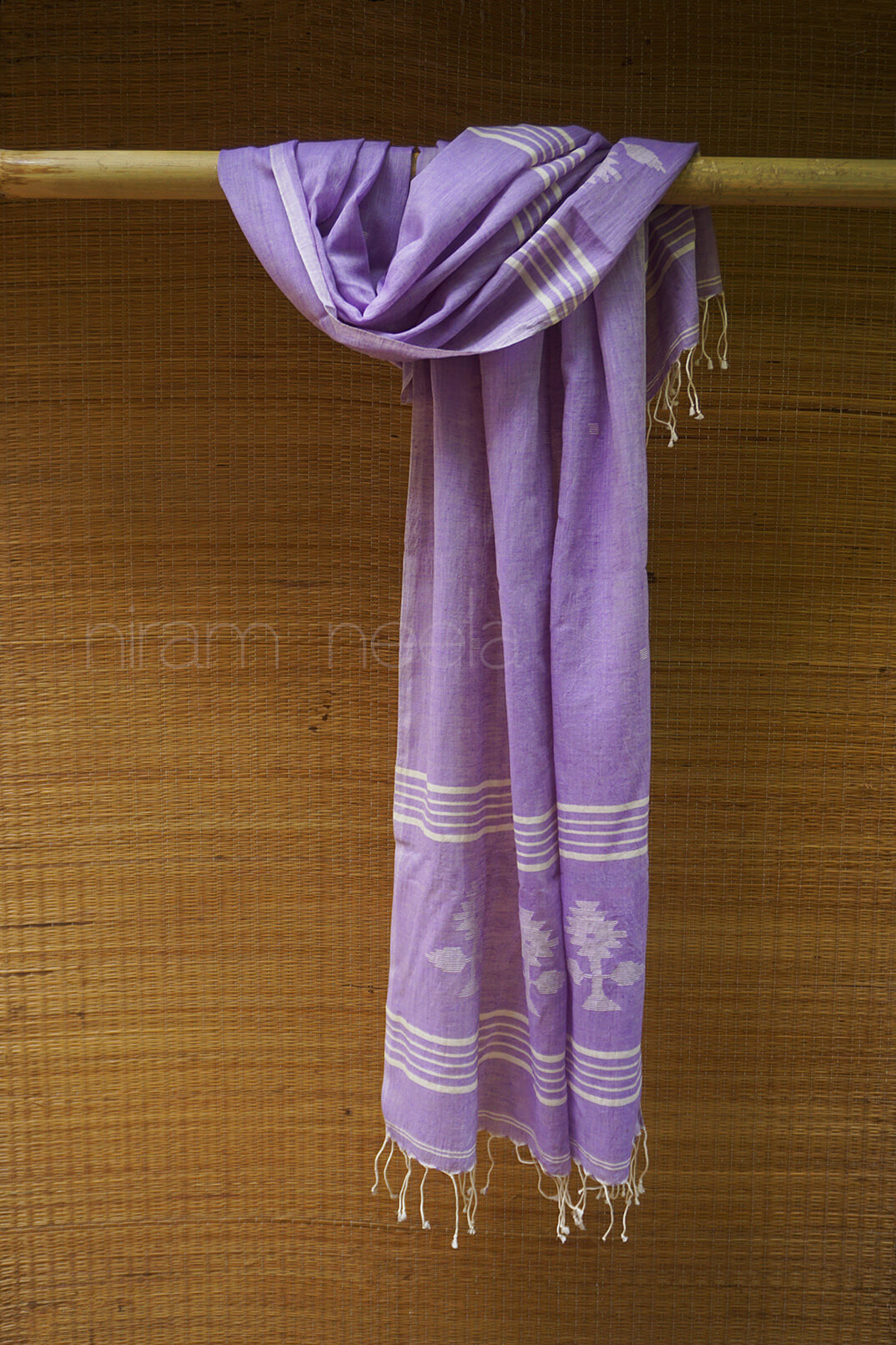 Soft violet scarf with white patterns hanging on a wooden rod against a wooden background