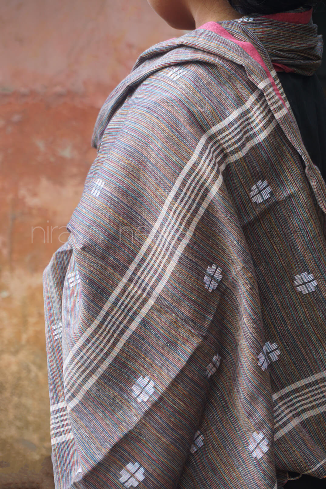 Person wearing a patterned shawl with a neutral background