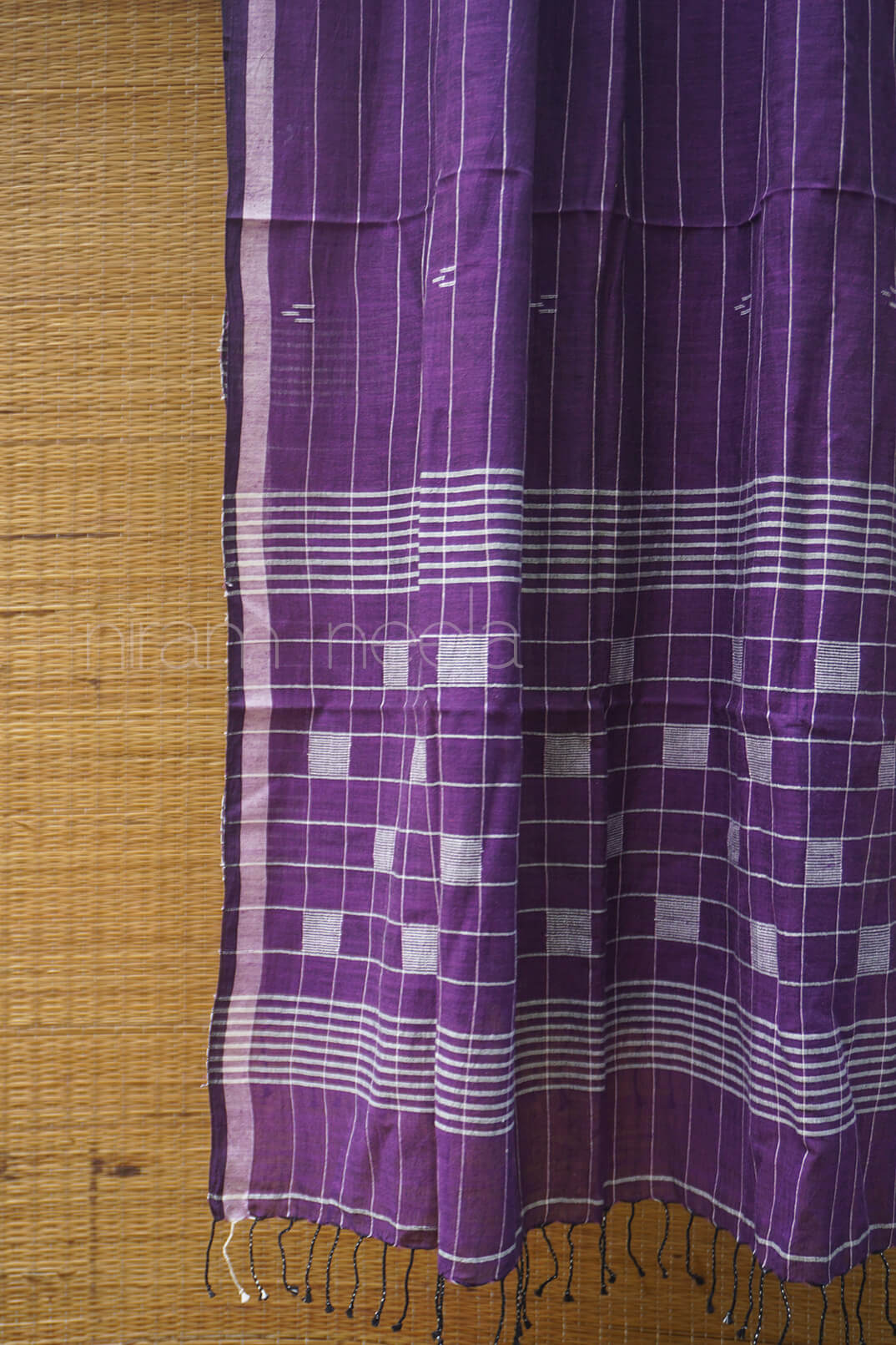 Purple and white checkered scarf with fringe on a wooden surface