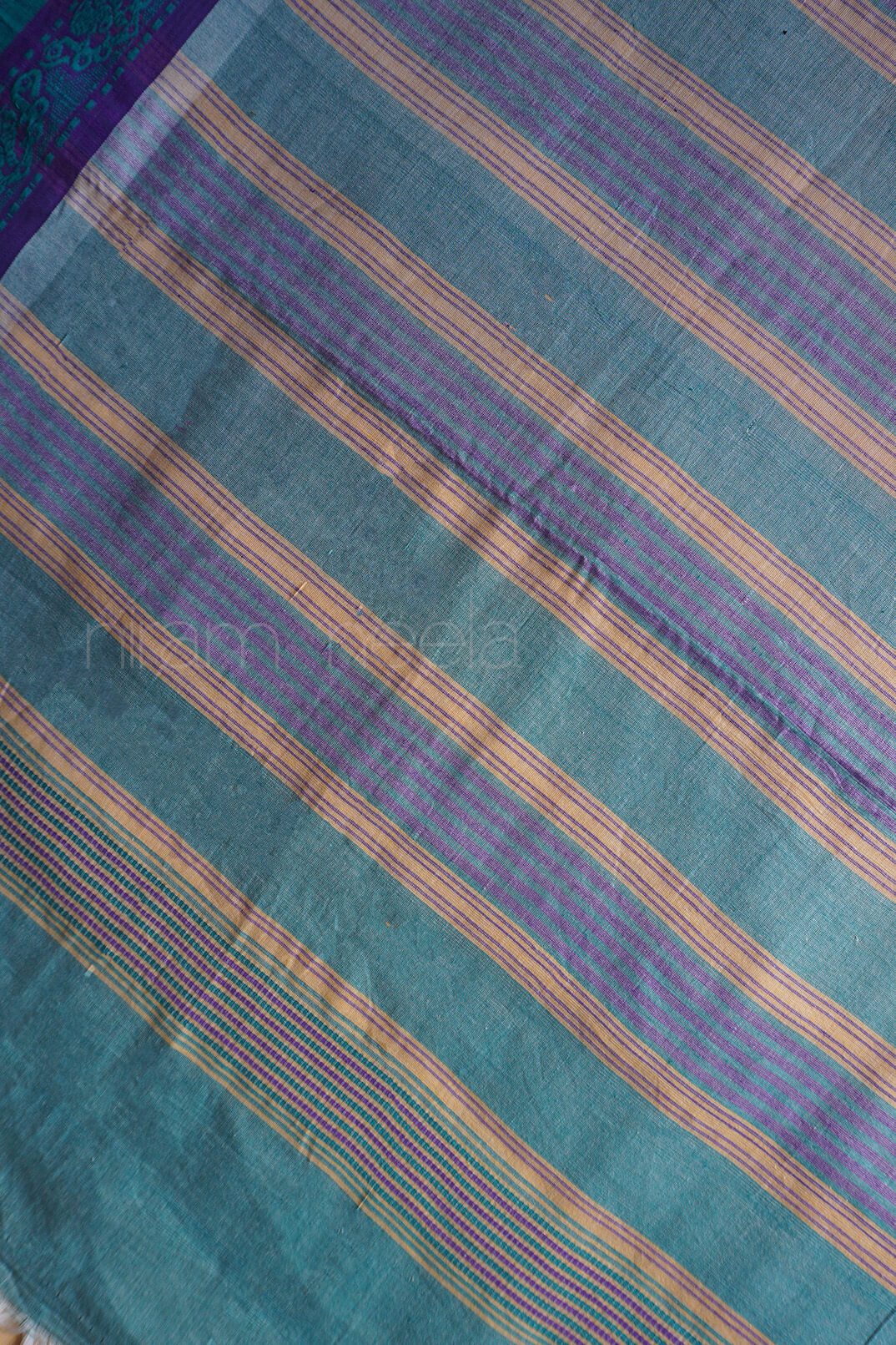 Close-up of striped fabric with teal, purple, and gold colors | Kozhikode saree by Niram Neela
