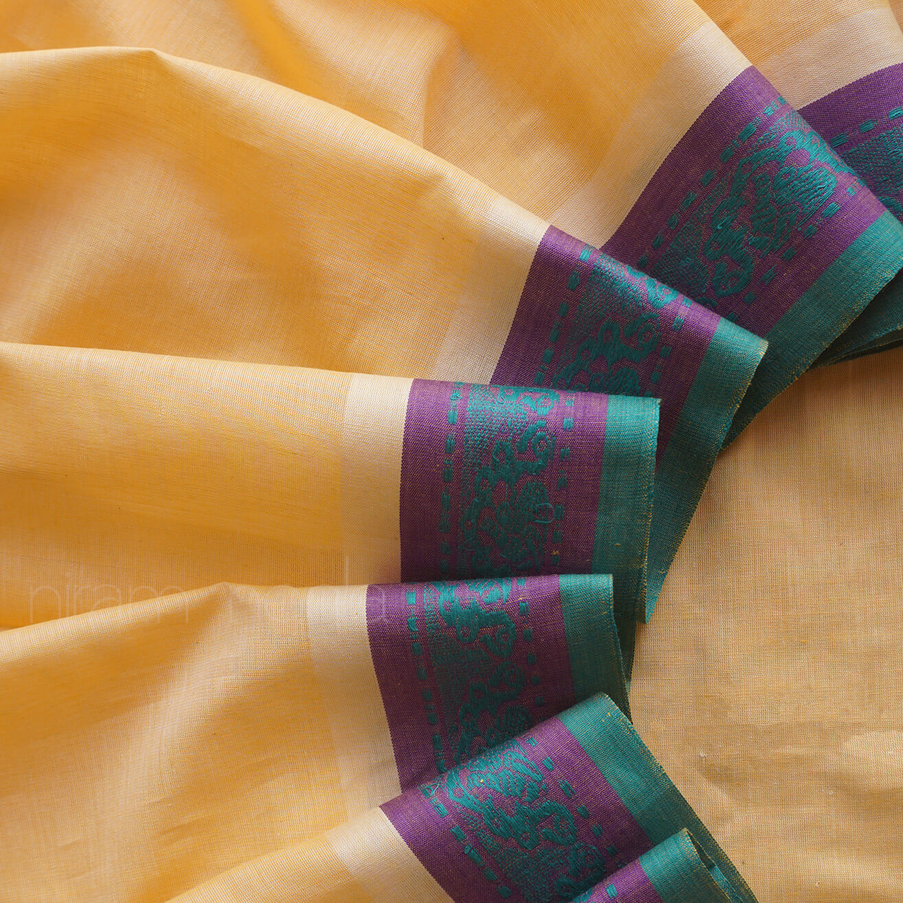 Close-up of a cream saree with purple and green border , brand 'niram neela' visible | Kozhikode saree  by Niram Neela