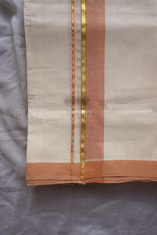 A close-up of a folded kasavu dhoti, with a warm off-white body, a vertical peach border, and narrow metallic gold stripes.