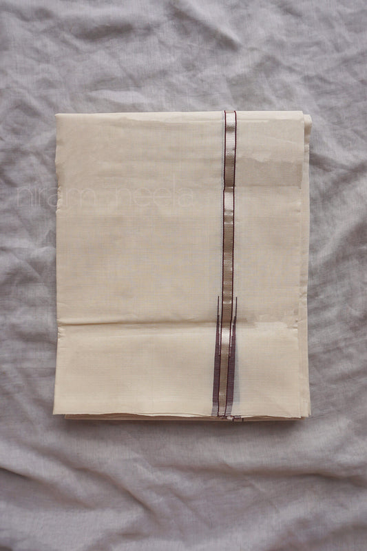 A folded cream-colored cotton dhoti , featuring a central metallic brown and silver vertical stripe, laid flat on a textured gray fabric background.